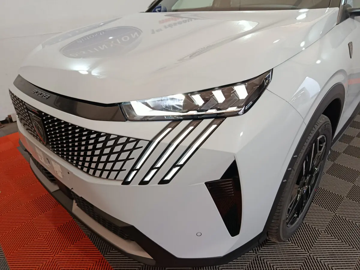 Vue 3/4 avant droit du Peugeot 3008 blanc avec calandre à motif losange et phares LED distinctifs en griffes.
