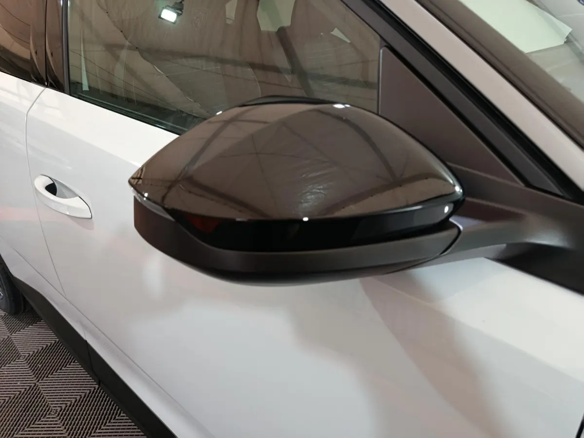 Rétroviseur noir côté gauche sur Peugeot 3008 blanc, vue rapprochée mettant en valeur le contraste des couleurs.