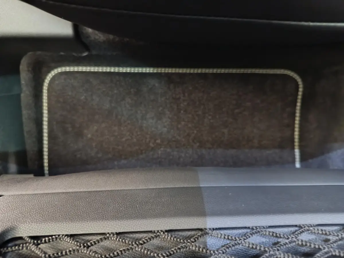 Gros plan sur le tapis de sol arrière noir avec surpiqûres blanches du Peugeot 3008 blanc 2025 version hybride.