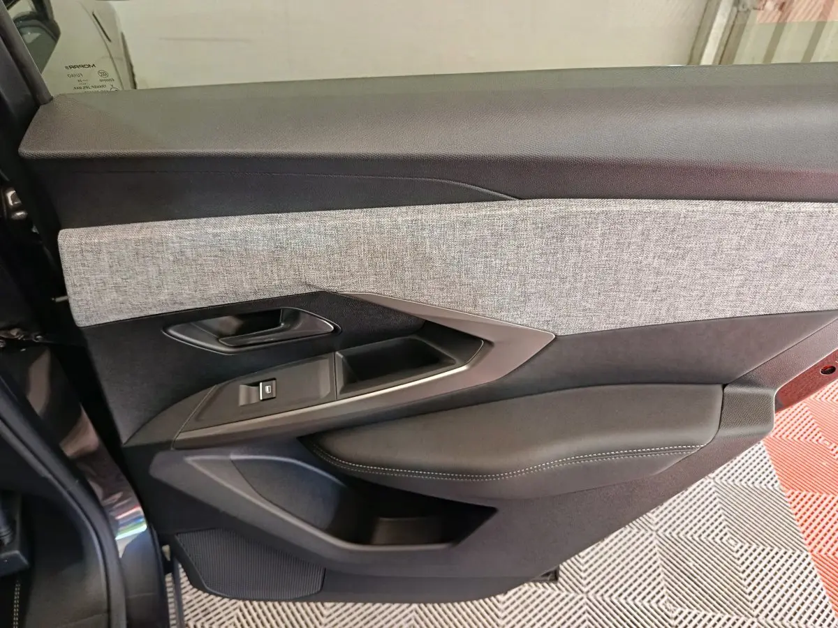 Gros plan sur la porte intérieure côté gauche du Peugeot 3008 blanc, avec garniture tissu gris et cuir noir.