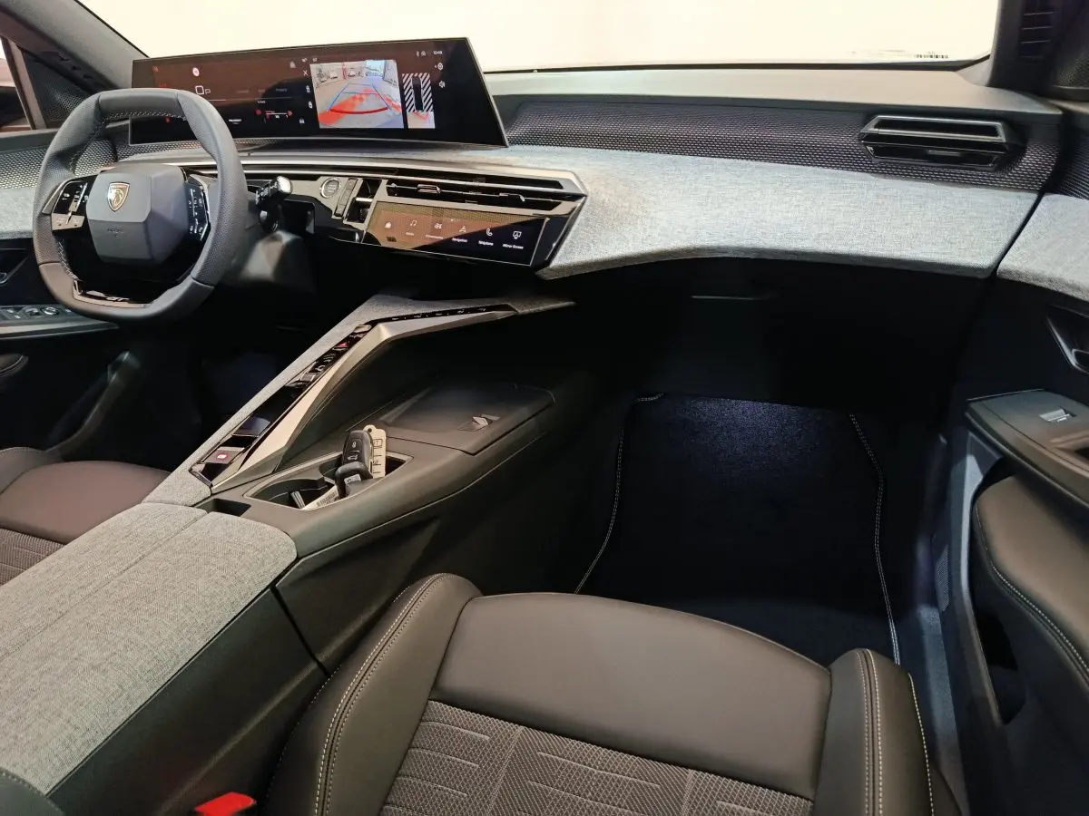 Intérieur avant droit du Peugeot 3008 blanc 2025, tableau de bord moderne avec écran tactile large et volant cuir multifonctions.