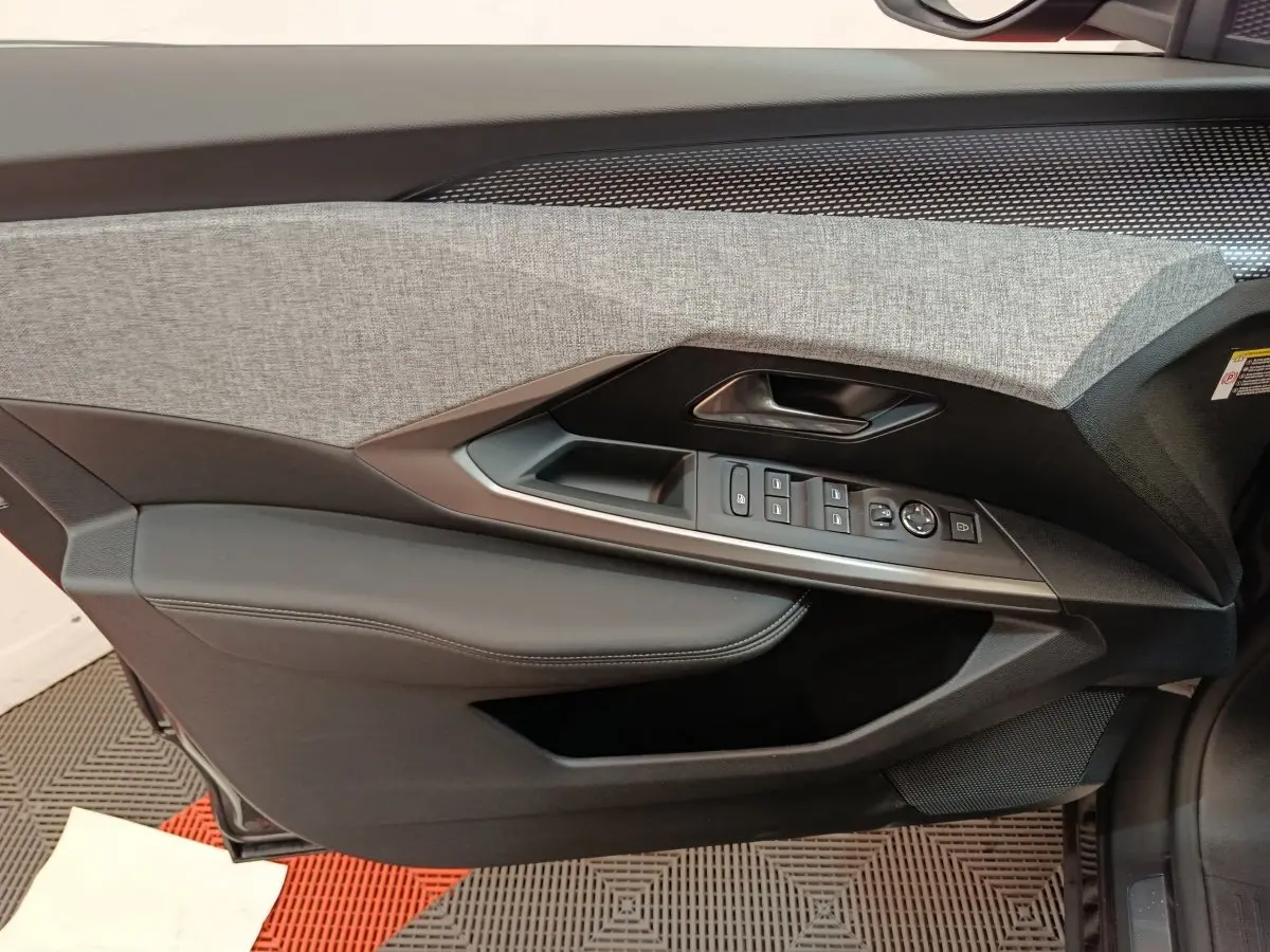 Vue intérieure côté gauche de la porte d'un Peugeot 3008 blanc 2025, avec garniture grise et commandes électriques.