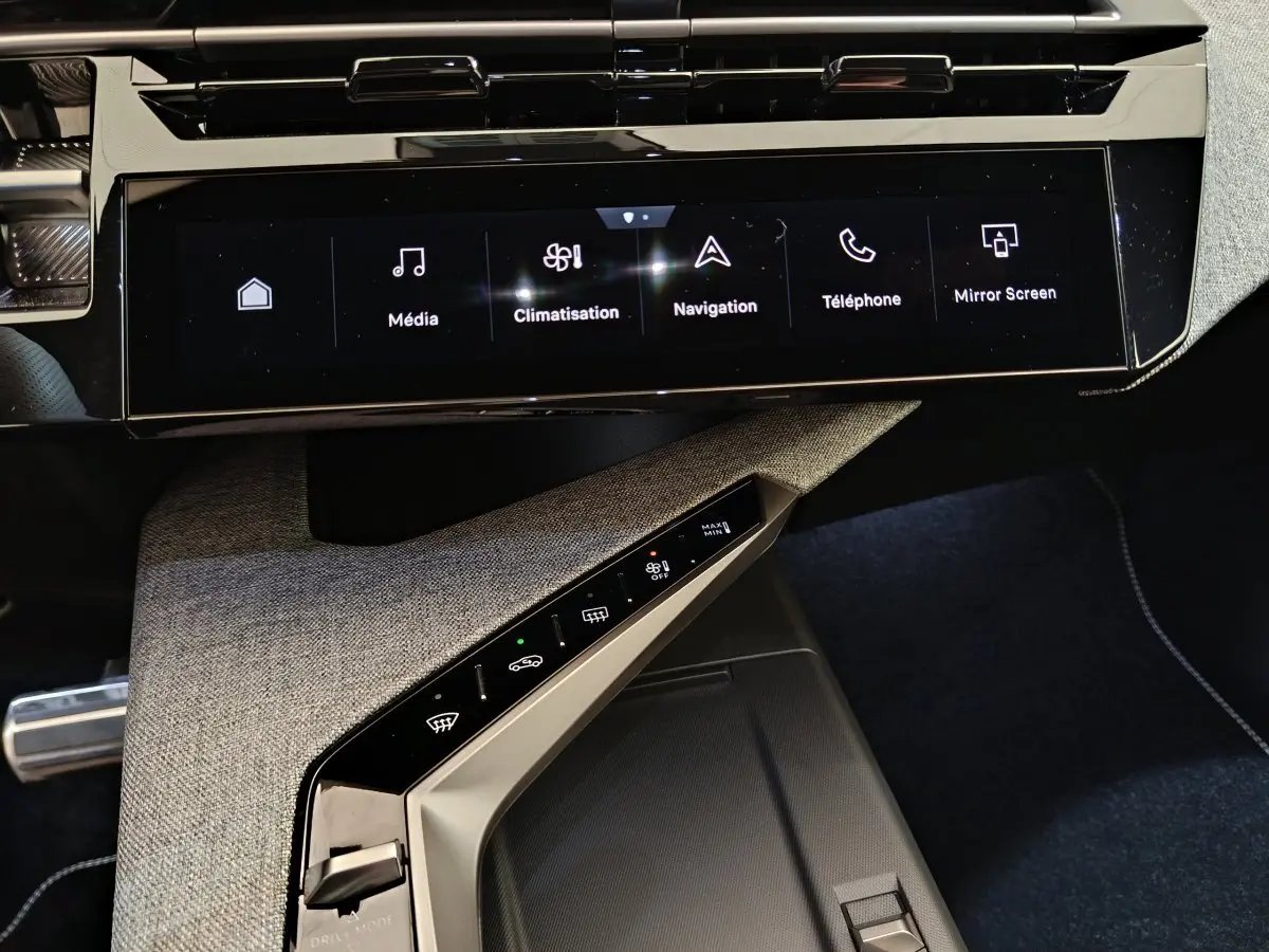 Vue rapprochée de la console centrale du Peugeot 3008 hybride 2025, avec écran tactile multifonctions et commandes climatisation.
