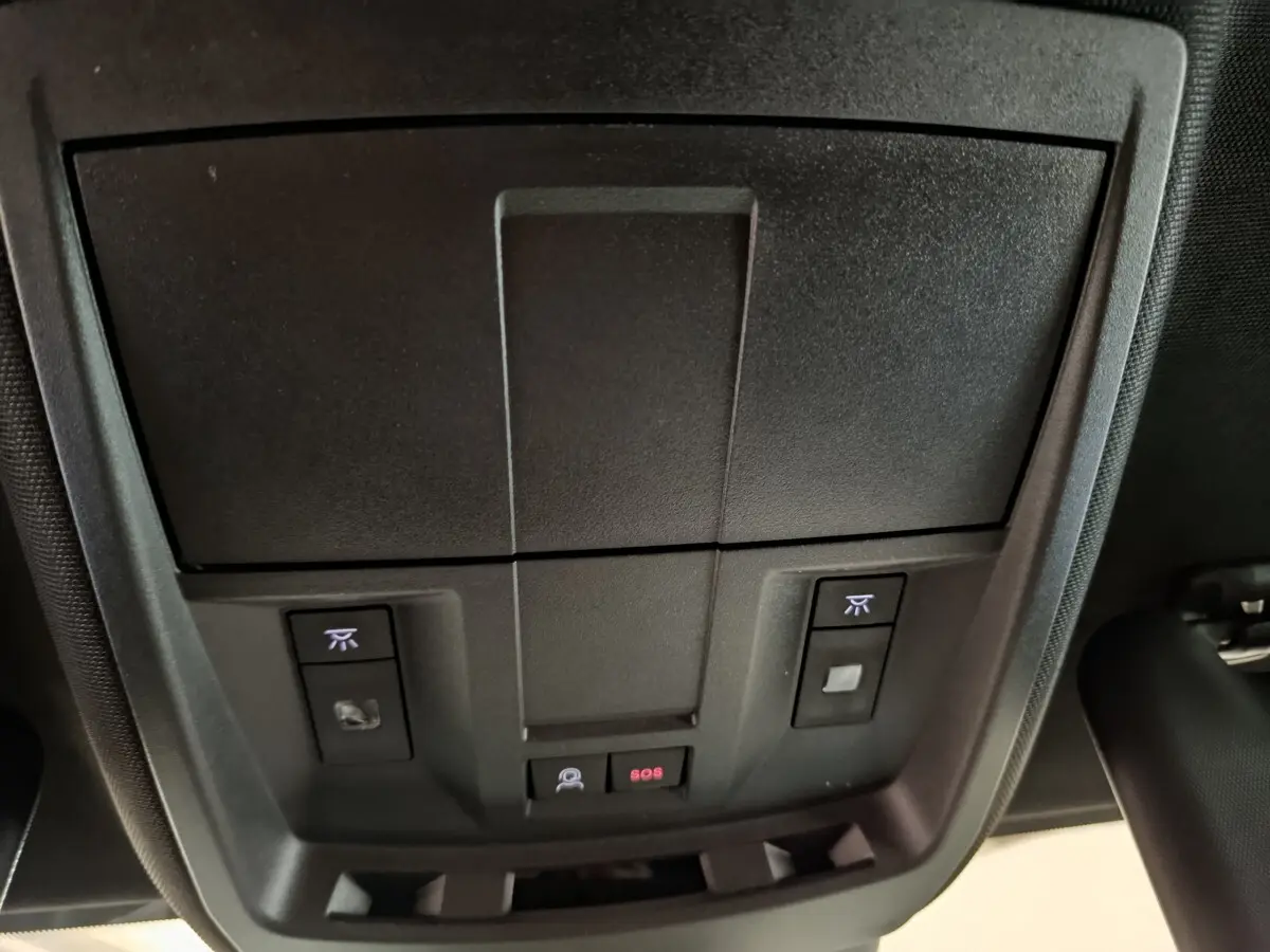 Vue intérieure du plafond de la Peugeot 3008 GT blanc 2025, avec commandes d'éclairage et bouton SOS éclairé rouge.