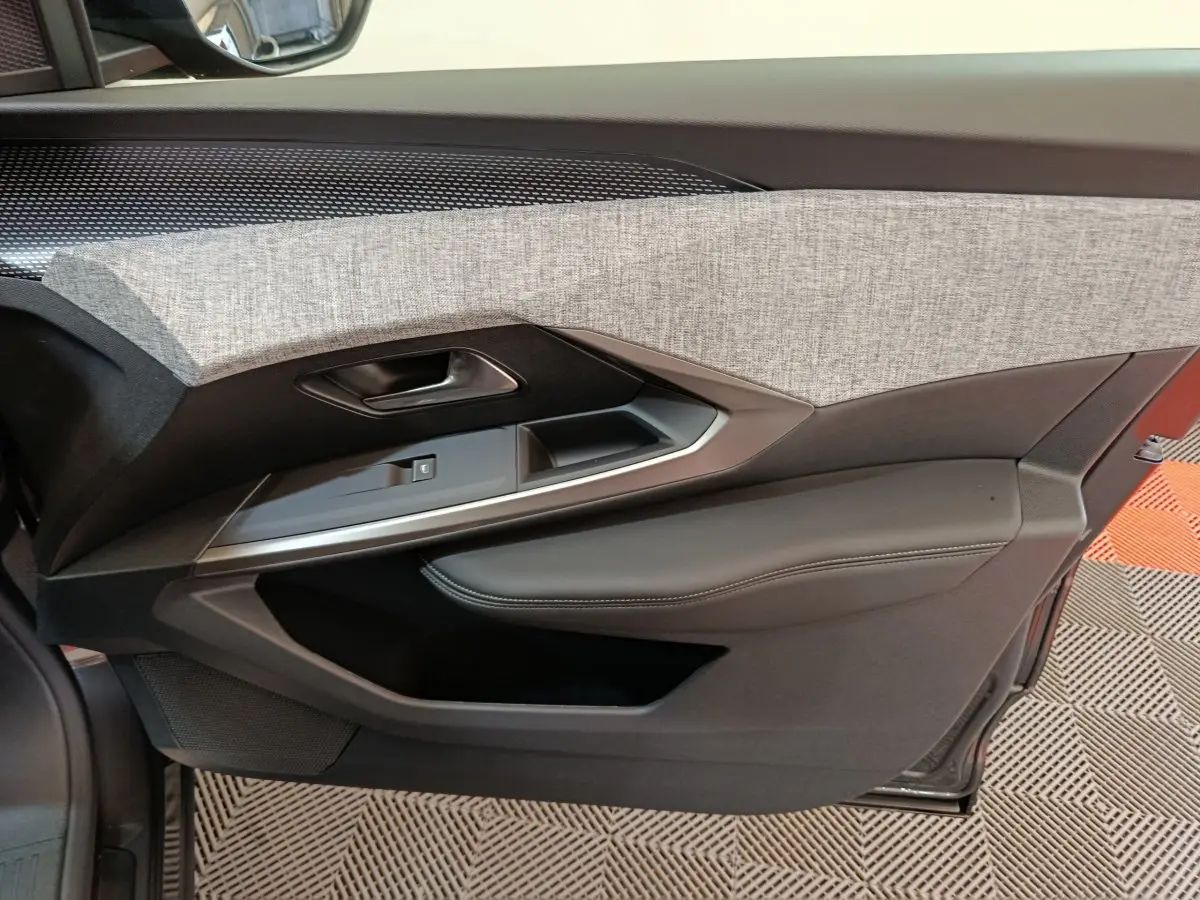 Gros plan sur la garniture intérieure côté gauche de porte du Peugeot 3008 blanc, avec tissu gris et cuir noir.