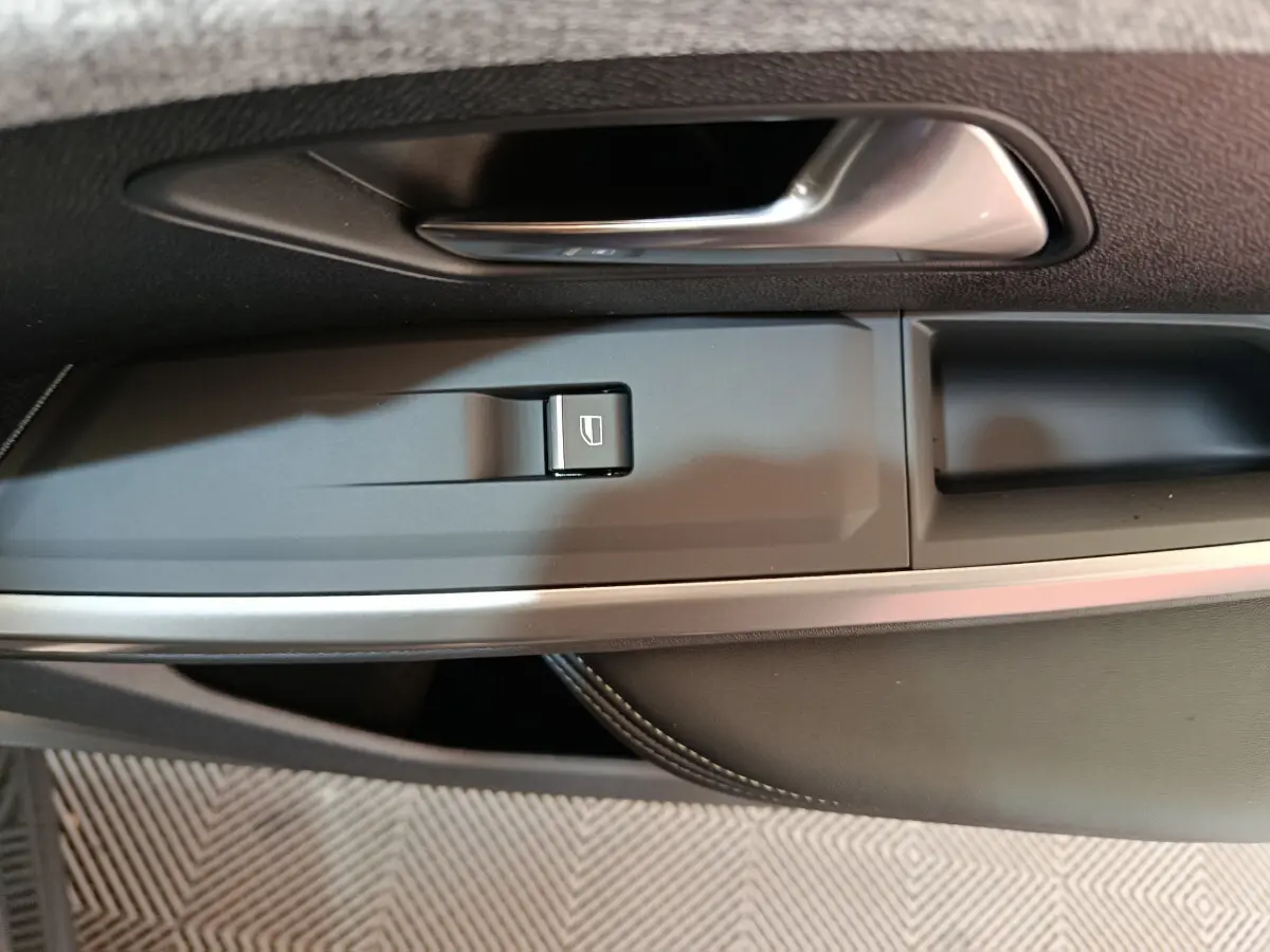 Poignée de porte intérieure côté gauche du Peugeot 3008 blanc 2025 avec bouton de commande de vitre électrique.