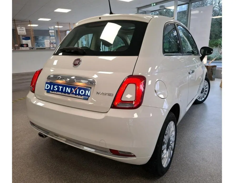 Vue 3/4 arrière droite d'une Fiat 500 blanche Bossa Nova avec badge Hybrid, en intérieur showroom.