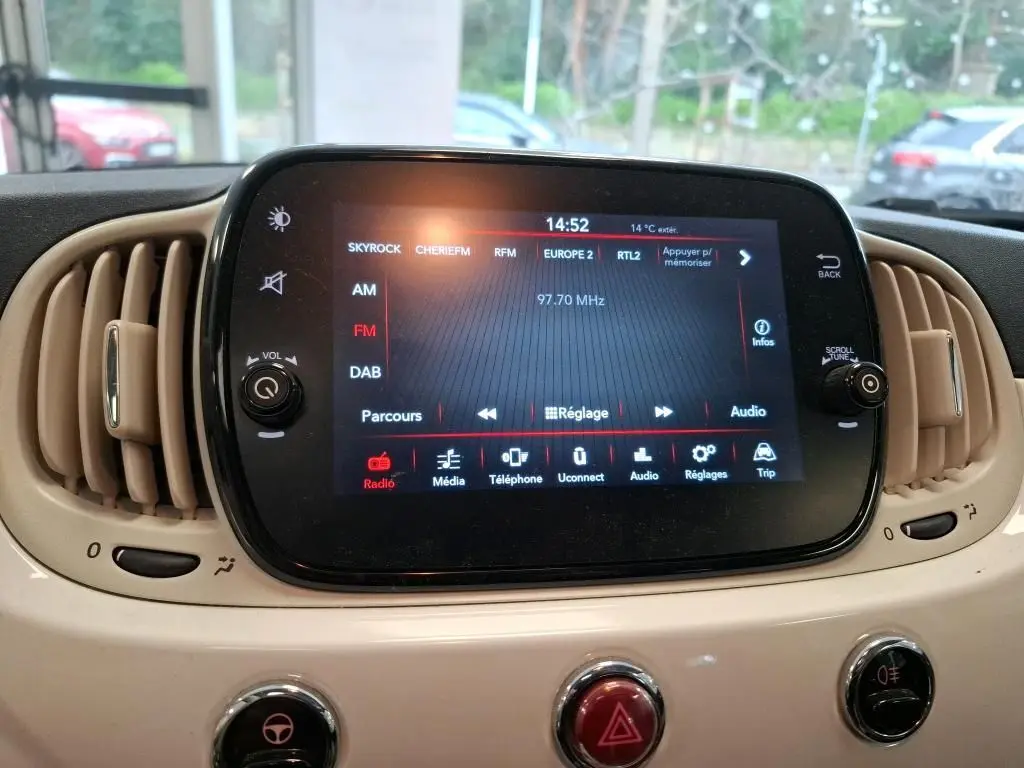 Écran tactile central du tableau de bord beige de la FIAT 500 blanche, affichant la radio FM à 97,70 MHz.