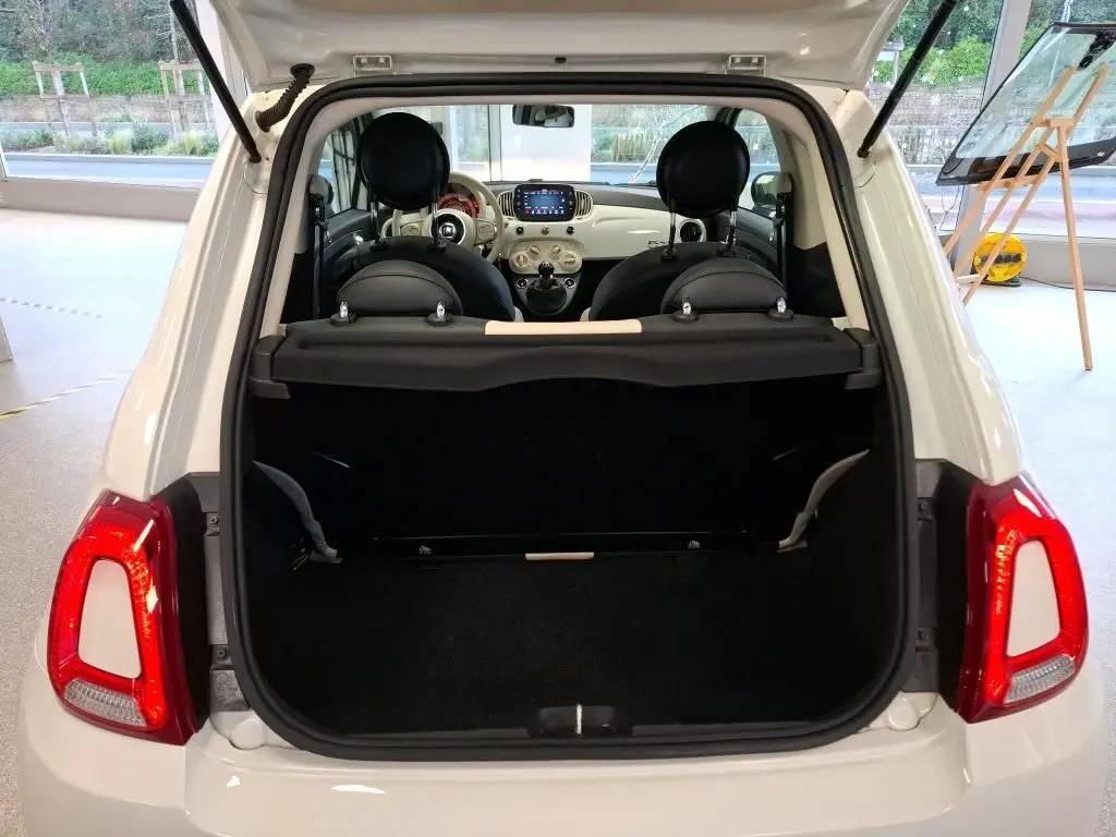 Vue arrière ouverte de la FIAT 500 2022 blanche Bossa Nova, montrant le coffre et l’intérieur avec tableau de bord visible.