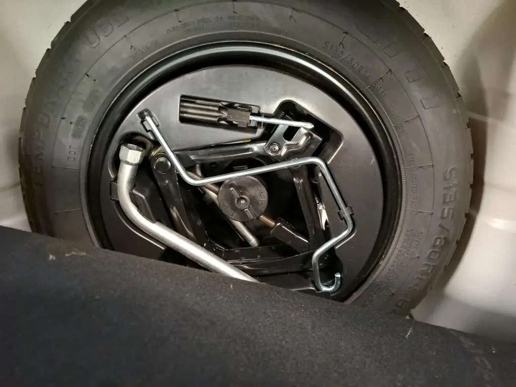 Gros plan sur la roue de secours et les outils de bord dans le coffre d'une Fiat 500 blanche Bossa Nova 2022.