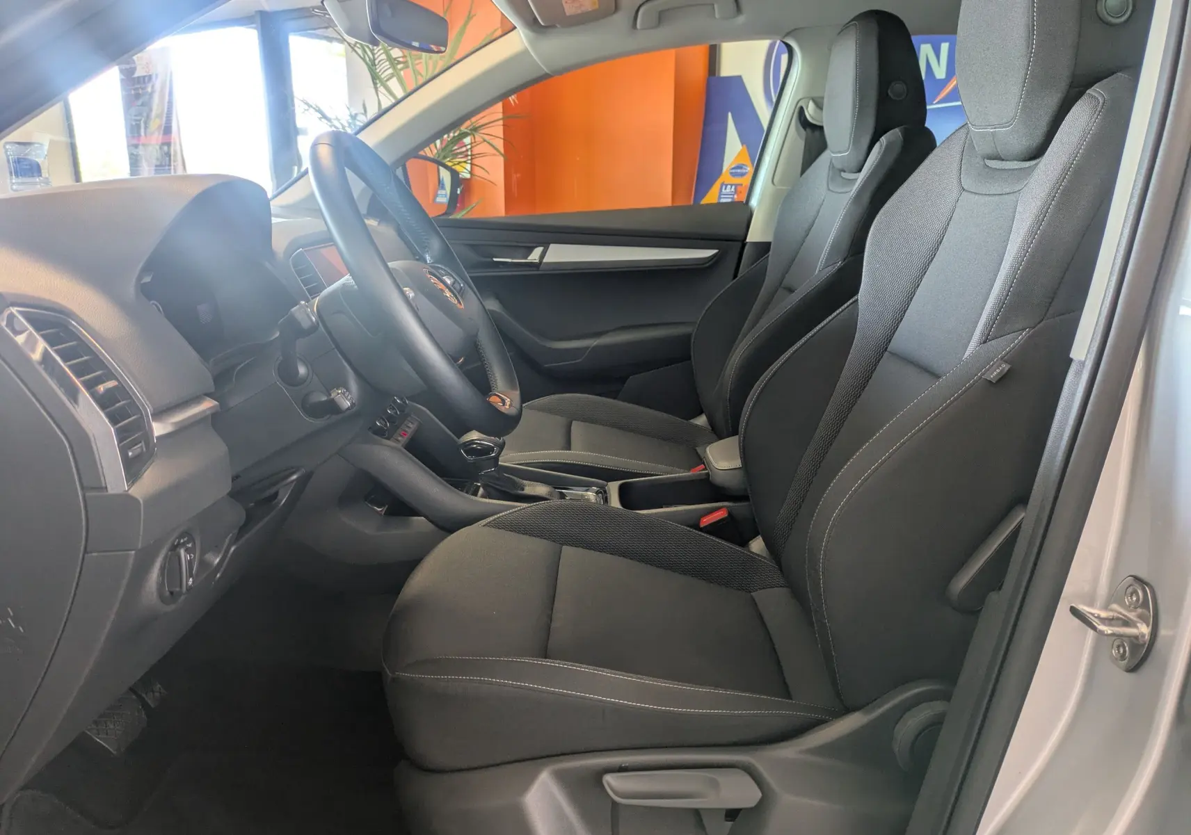 Vue intérieure côté conducteur du Skoda Karoq gris argent 2023, sièges tissu noirs et tableau de bord moderne.