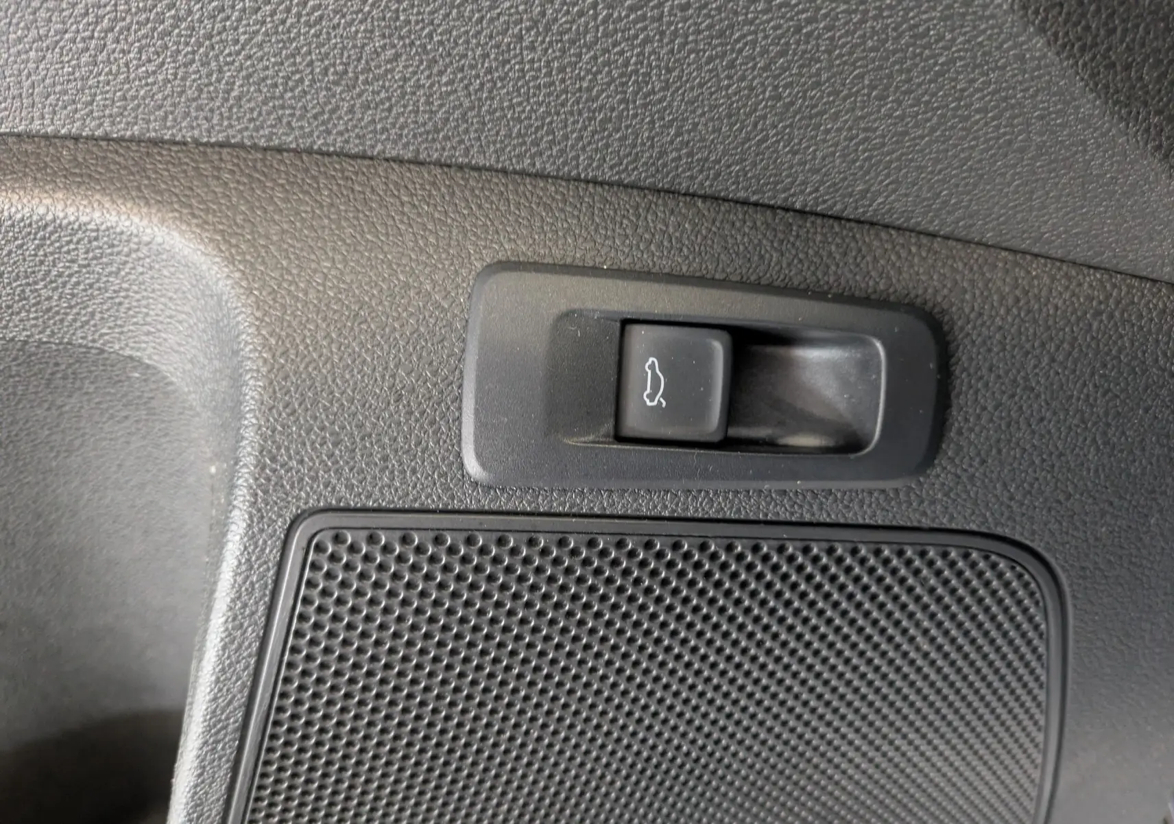 Gros plan sur le bouton d'ouverture électrique du hayon dans l'habitacle d'un Skoda Karoq gris argent 2023.