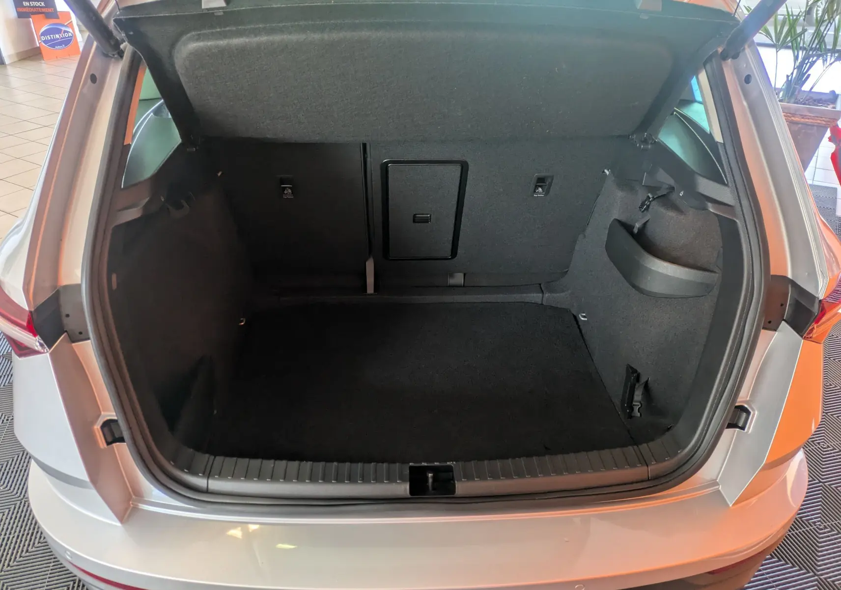 Coffre ouvert vu de l'arrière d'un Skoda Karoq gris argent 2023, montrant l'espace de chargement vide.