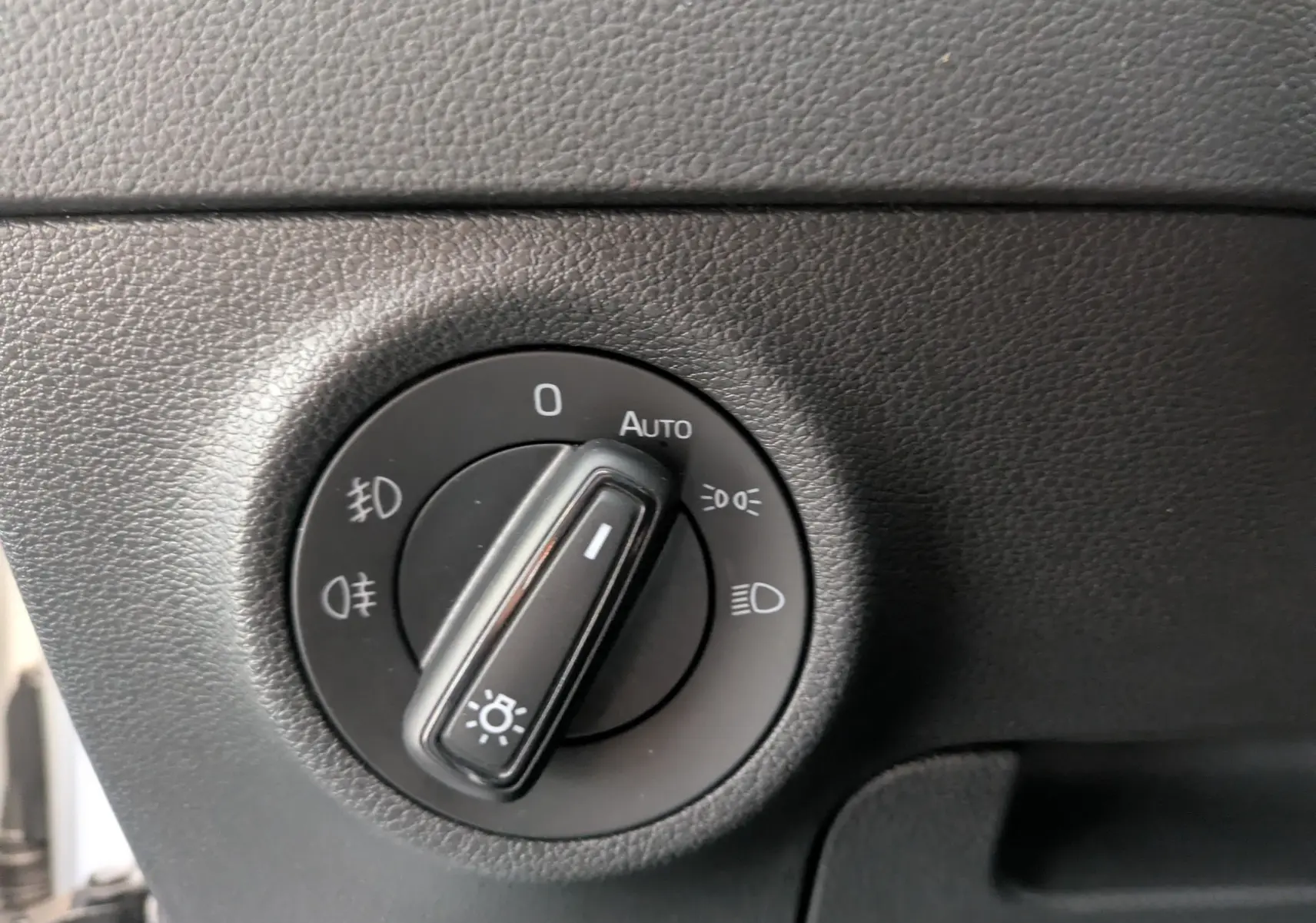 Gros plan sur le bouton de commande des phares dans l’habitacle du Skoda Karoq gris argent 2023.