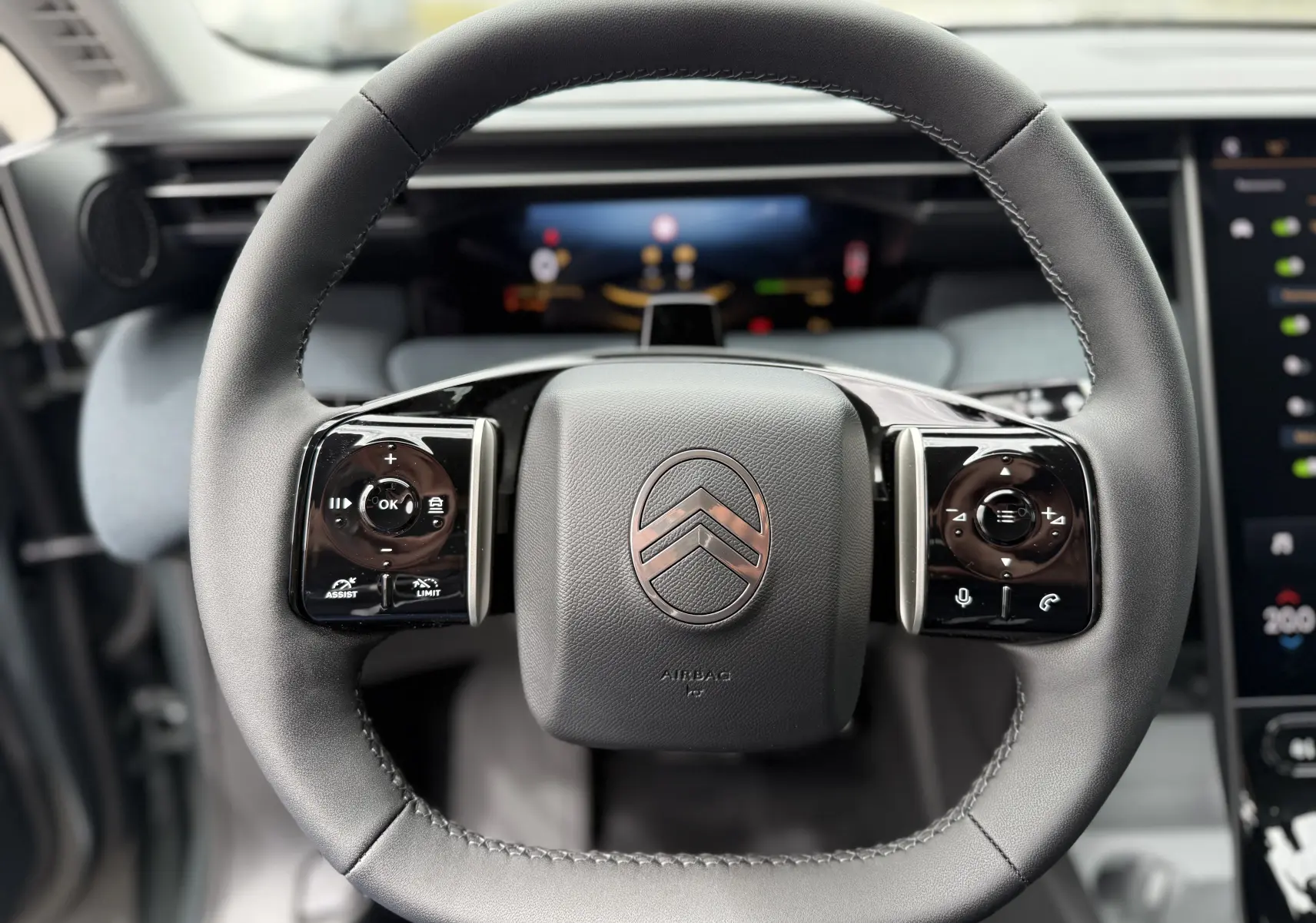 Vue rapprochée du volant noir du Citroën C5 Aircross II Hybrid 2026, avec commandes tactiles intégrées et logo central.