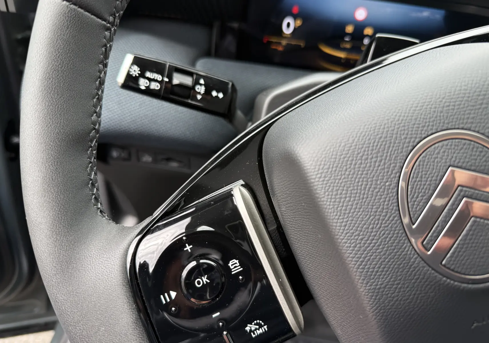 Gros plan sur le volant gris du Citroën C5 Aircross II Hybrid avec commandes intégrées et logo central visible.