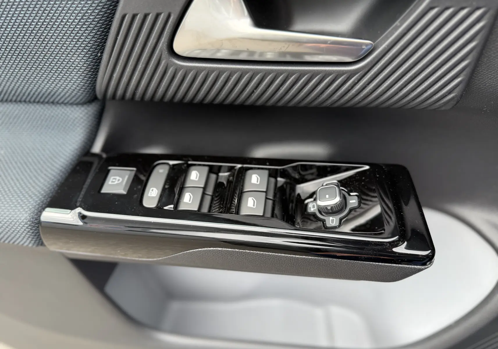 Gros plan sur les commandes de lève-vitres et réglage des rétroviseurs côté conducteur d'une Citroën C5 Aircross II Hybrid 2026.