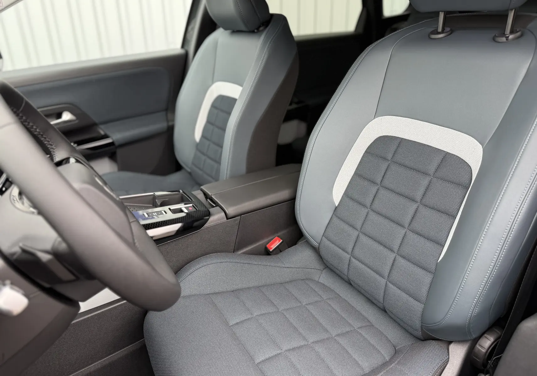 Vue rapprochée des sièges avant gris et noirs du Citroën C5 Aircross II Hybrid 2026, avec console centrale visible.