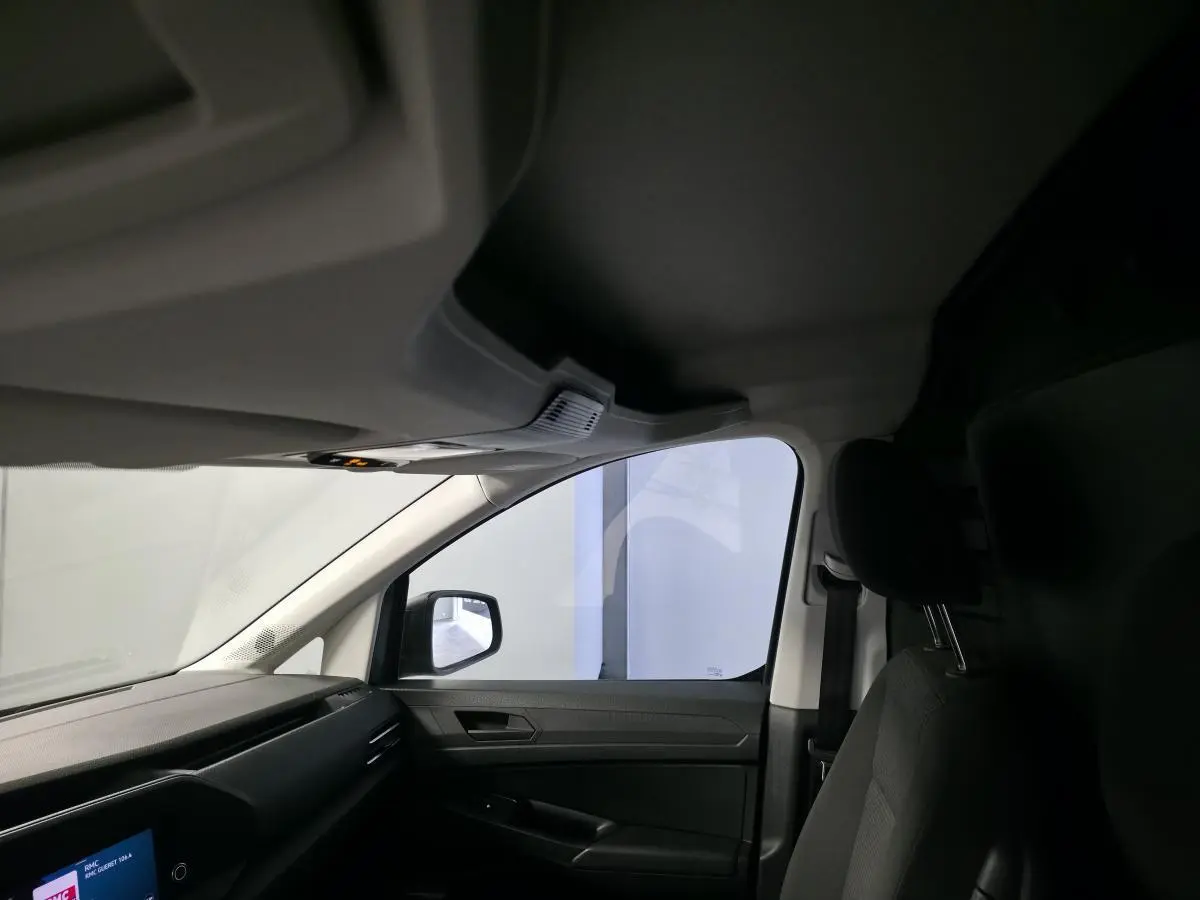 Vue intérieure côté passager avant du Volkswagen Caddy Cargo gris, mettant en valeur le siège et la portière.