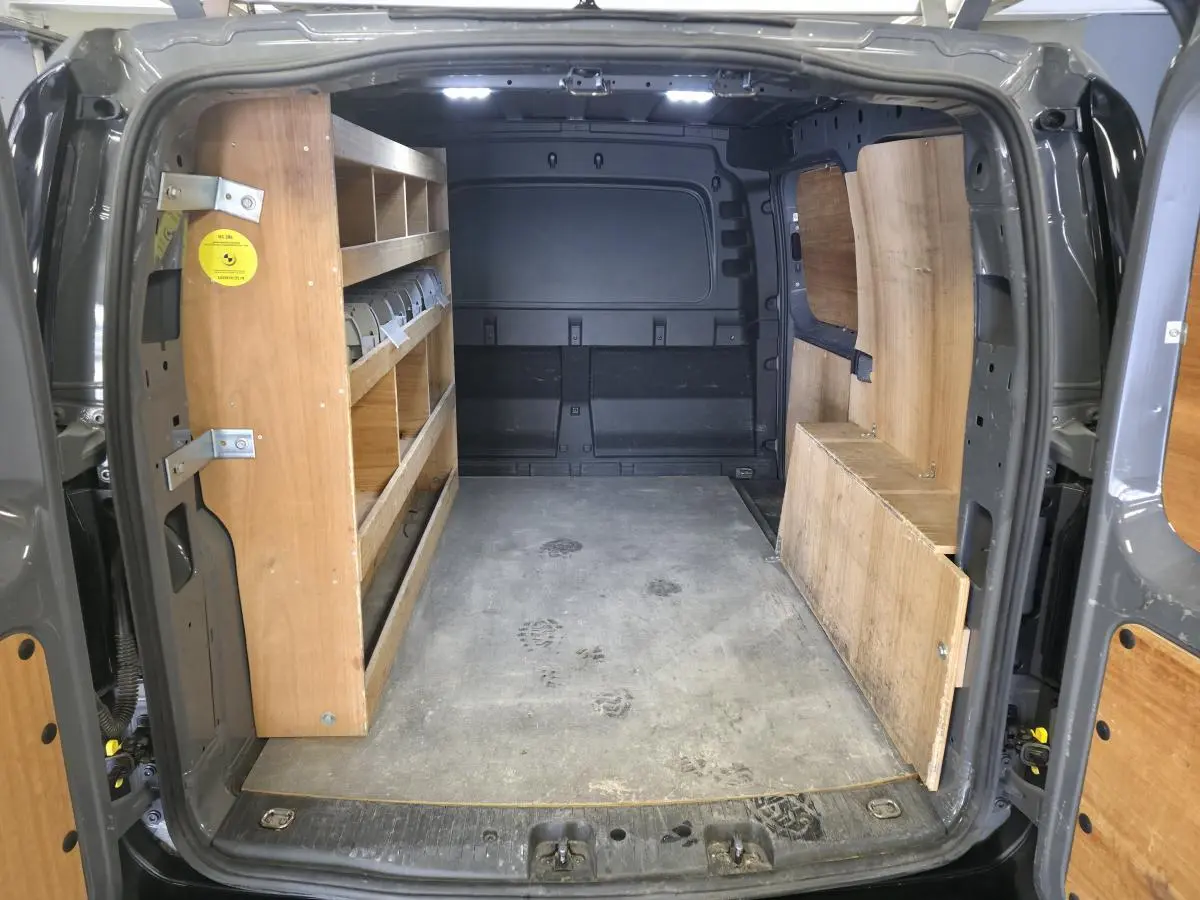 Vue intérieure arrière du Volkswagen Caddy Cargo gris 2022, montrant l'espace de chargement avec étagères en bois.