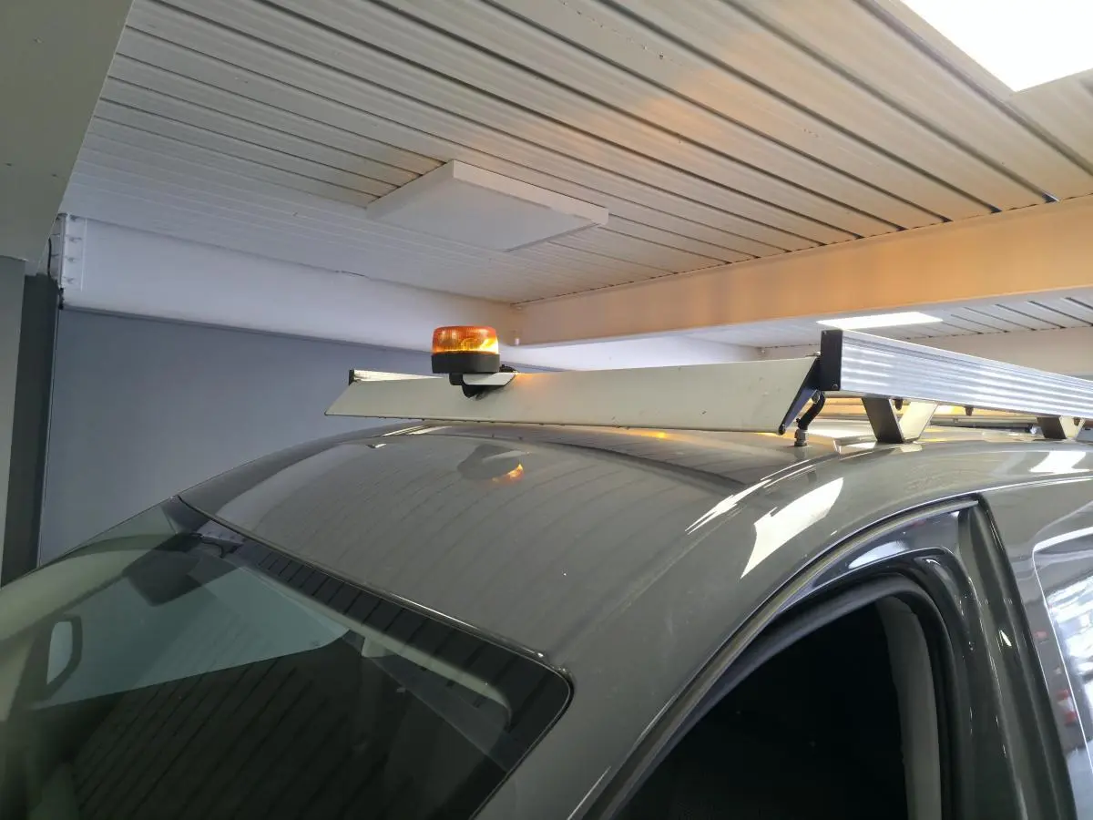 Vue rapprochée du toit gris d’un Volkswagen Caddy Cargo 2022 avec galerie et gyrophare orange installé.