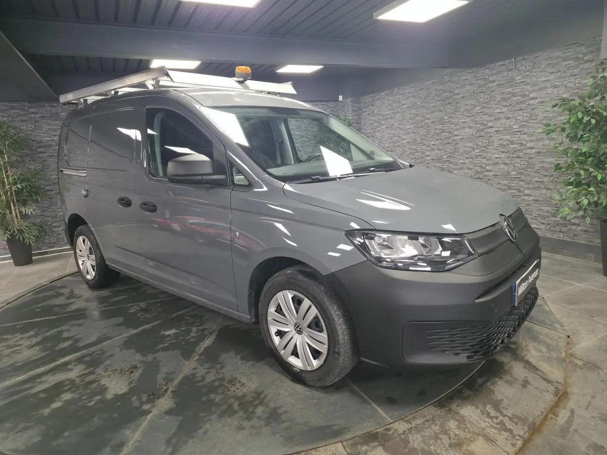 Volkswagen Caddy Cargo gris en 3/4 avant droit avec galerie de toit et jantes acier noires.
