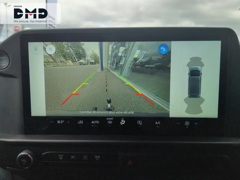 Écran tactile montrant la caméra de recul du Ford Transit Custom blanc Glacier en vue arrière avec lignes de guidage colorées.