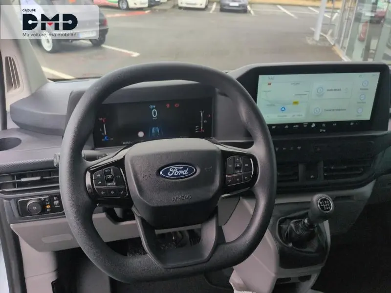 Vue frontale de l’intérieur du Ford Transit Custom 2024, volant multifonctions et écran tactile large visibles.