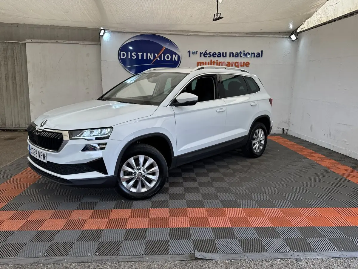 Vue 3/4 avant droite d’un Skoda Karoq blanc avec calandre noire et jantes alliage dans un showroom.