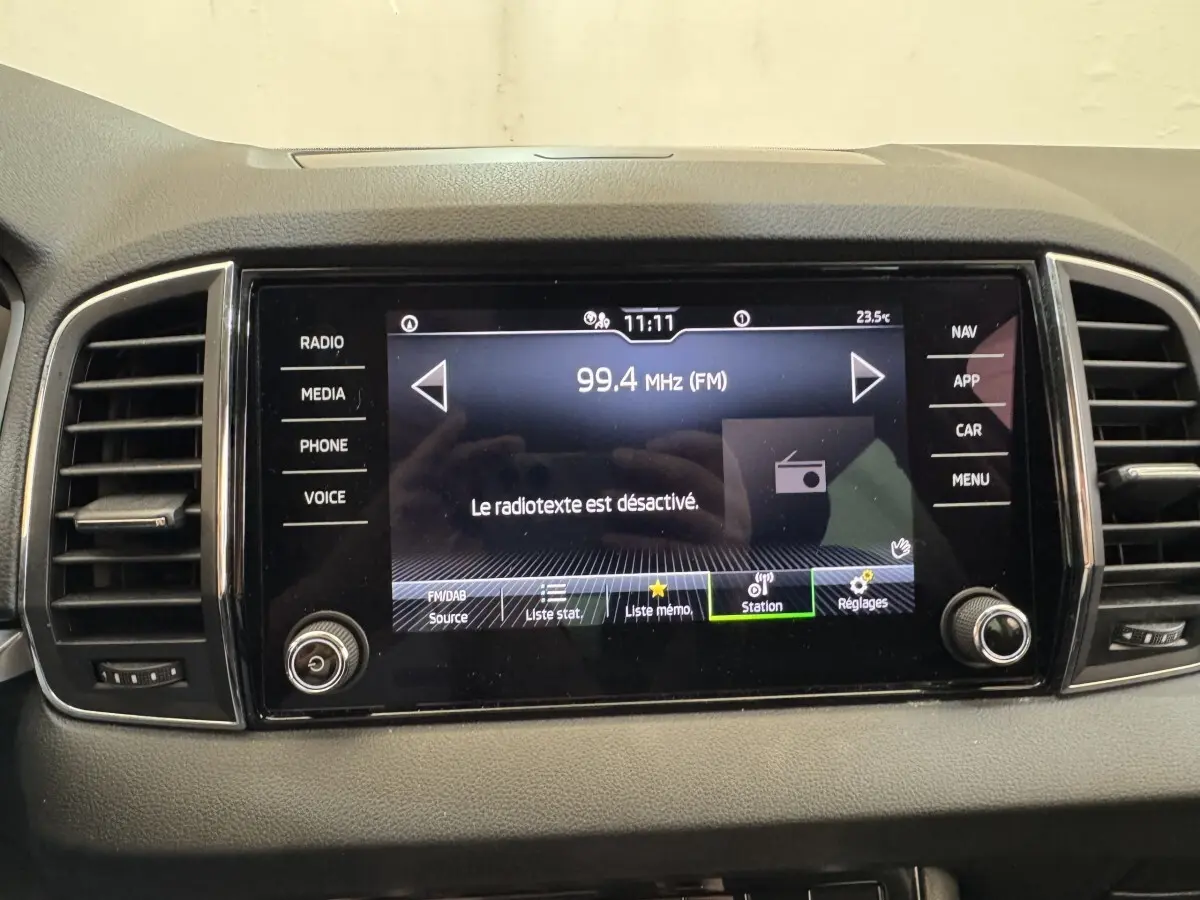 Écran tactile central du tableau de bord du Skoda Karoq blanc, affichant la radio FM à 99,4 MHz.