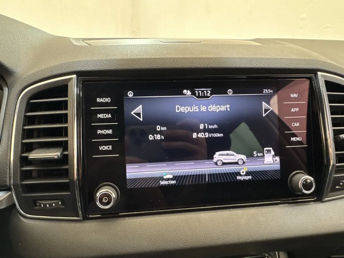 Écran tactile central du tableau de bord du Skoda Karoq blanc, affichant les données de trajet et consommation.