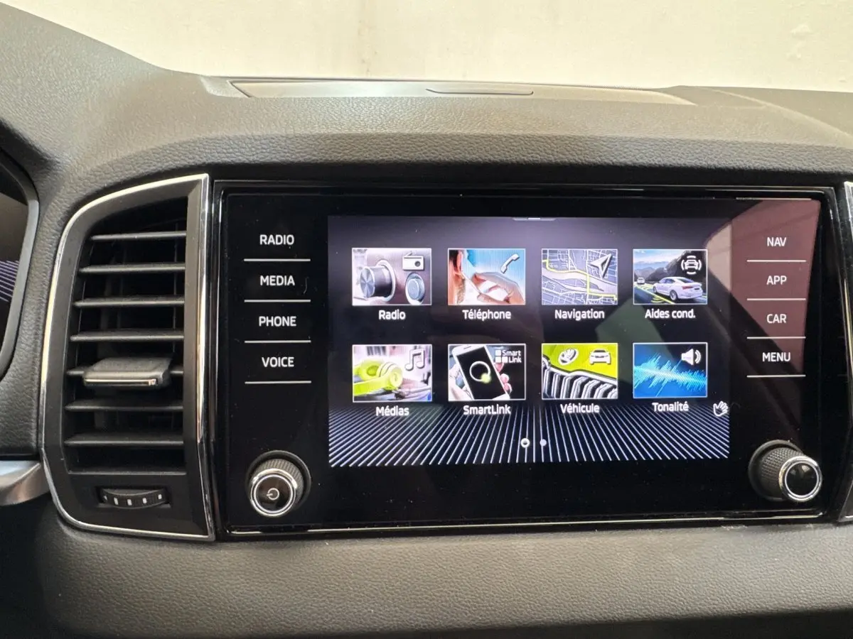 Écran tactile central du tableau de bord du Skoda Karoq 2024 affichant les menus radio, téléphone, navigation et aides à la conduite.