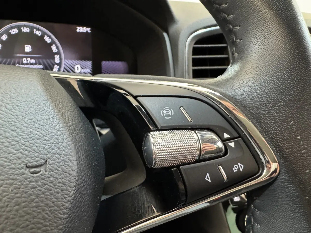 Gros plan sur les commandes multifonctions à droite du volant cuir du Skoda Karoq 2024, affichage digital en arrière-plan.