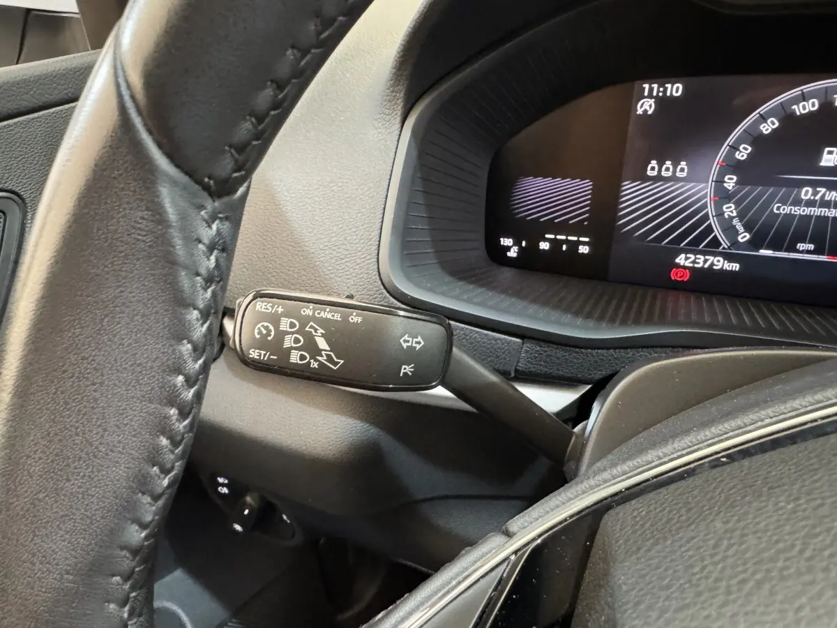 Gros plan sur le combiné d'instruments et la commande multifonction à gauche du volant cuir dans un Skoda Karoq blanc 2024.