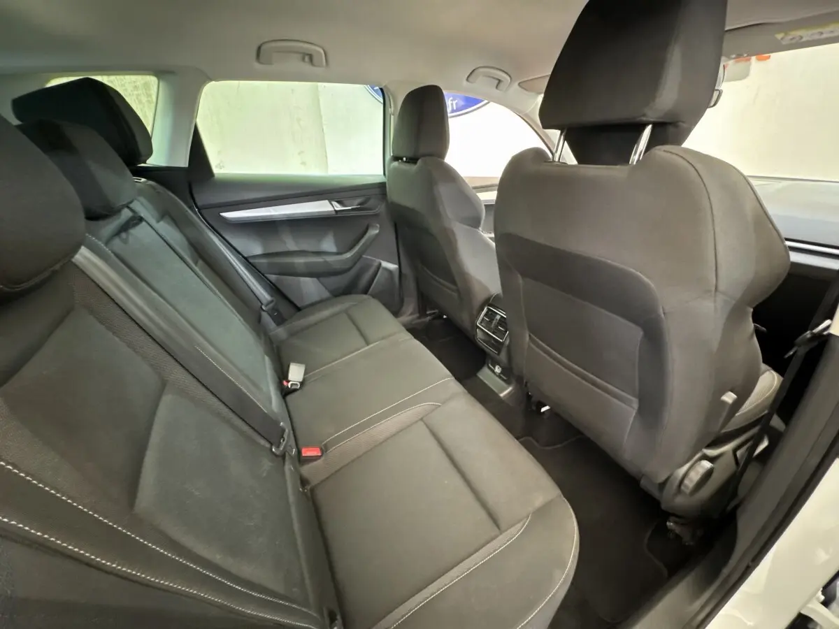 Vue intérieure arrière montrant les sièges noirs du Skoda Karoq 2024 avec accoudoirs centraux et espace passagers.