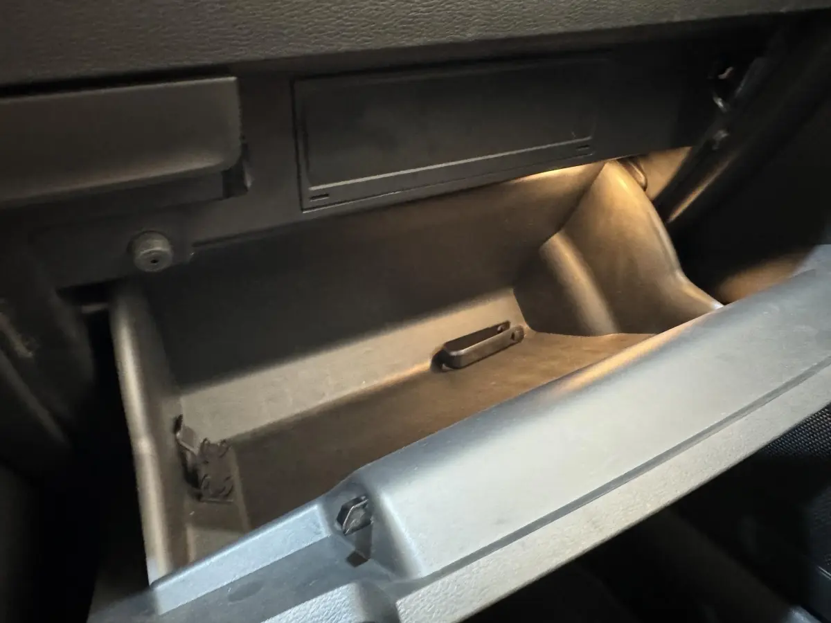 Gros plan sur la boîte à gants ouverte et éclairée à l'intérieur d'un Skoda Karoq blanc 2024.