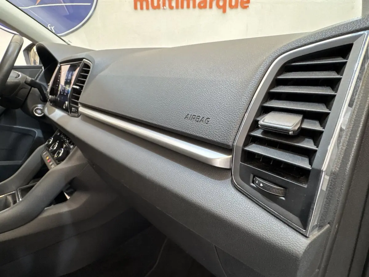 Vue intérieure côté passager du tableau de bord noir du Skoda Karoq 2024 avec aérateurs et écran tactile visible.