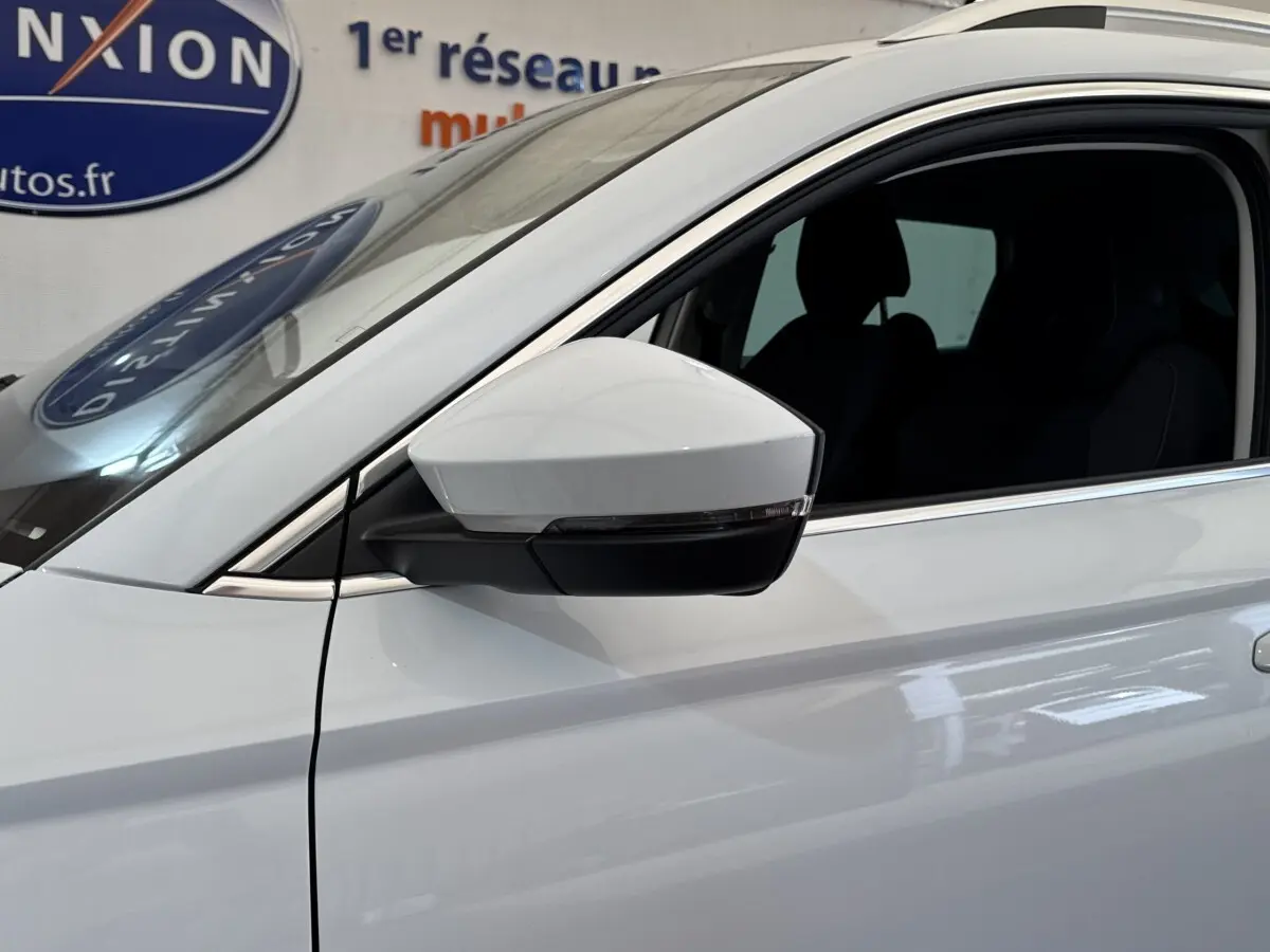 Gros plan sur le rétroviseur côté gauche d’un Skoda Karoq blanc 2024 avec fenêtre ouverte et contours noirs.