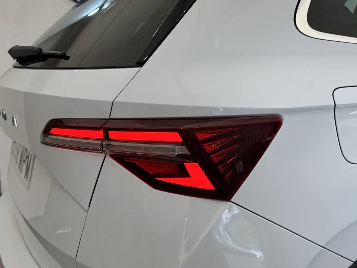 Gros plan sur le feu arrière droit rouge allumé d’un SKODA KAROQ blanc, vue arrière côté droit.