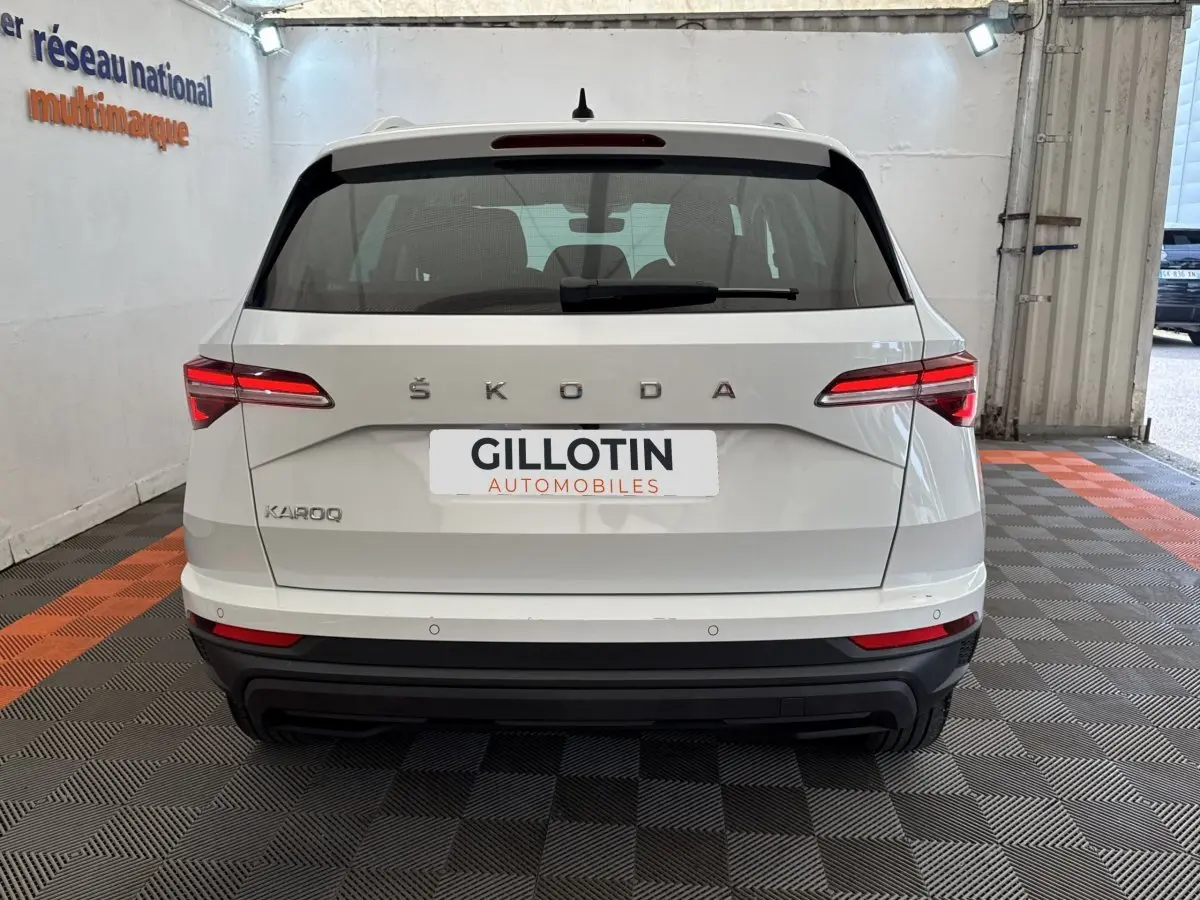 Vue arrière d'un Skoda Karoq blanc 2024 dans un garage avec feux arrière LED et logo ŠKODA visible.