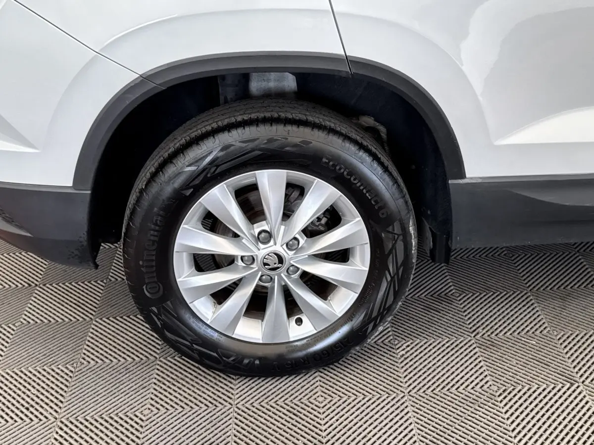 Gros plan sur la roue avant droite d’un Skoda Karoq blanc, avec jante argentée et pneu Continental.