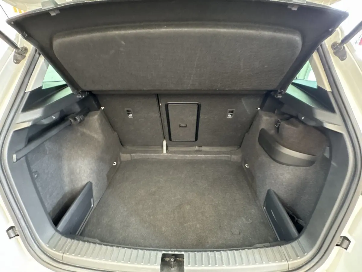 Vue intérieure du coffre ouvert du Skoda Karoq blanc 2024, montrant un espace de rangement propre et spacieux.