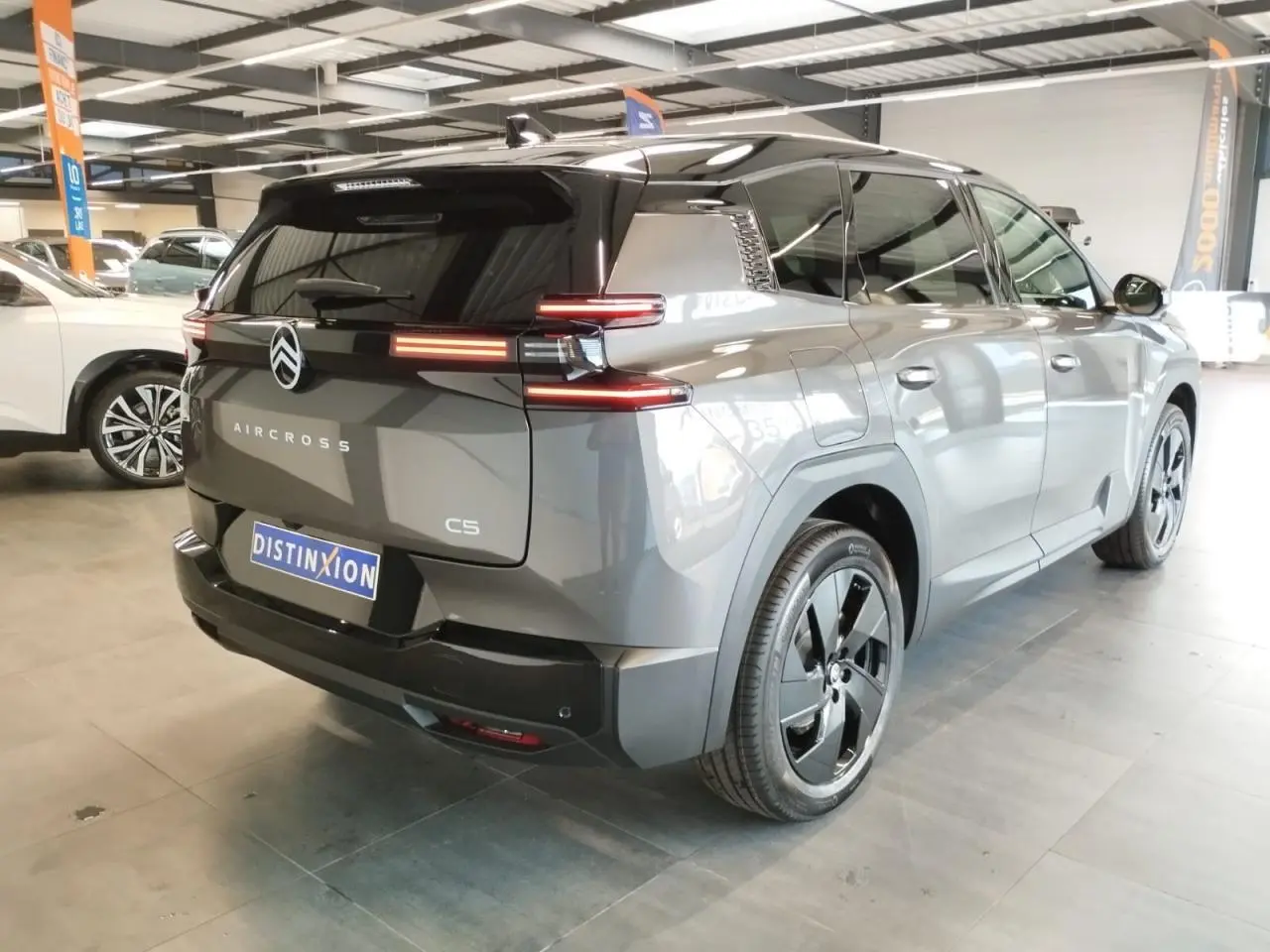 Vue 3/4 arrière droite d'un Citroën C5 Aircross gris platine avec toit noir et jantes alliage 19 pouces.
