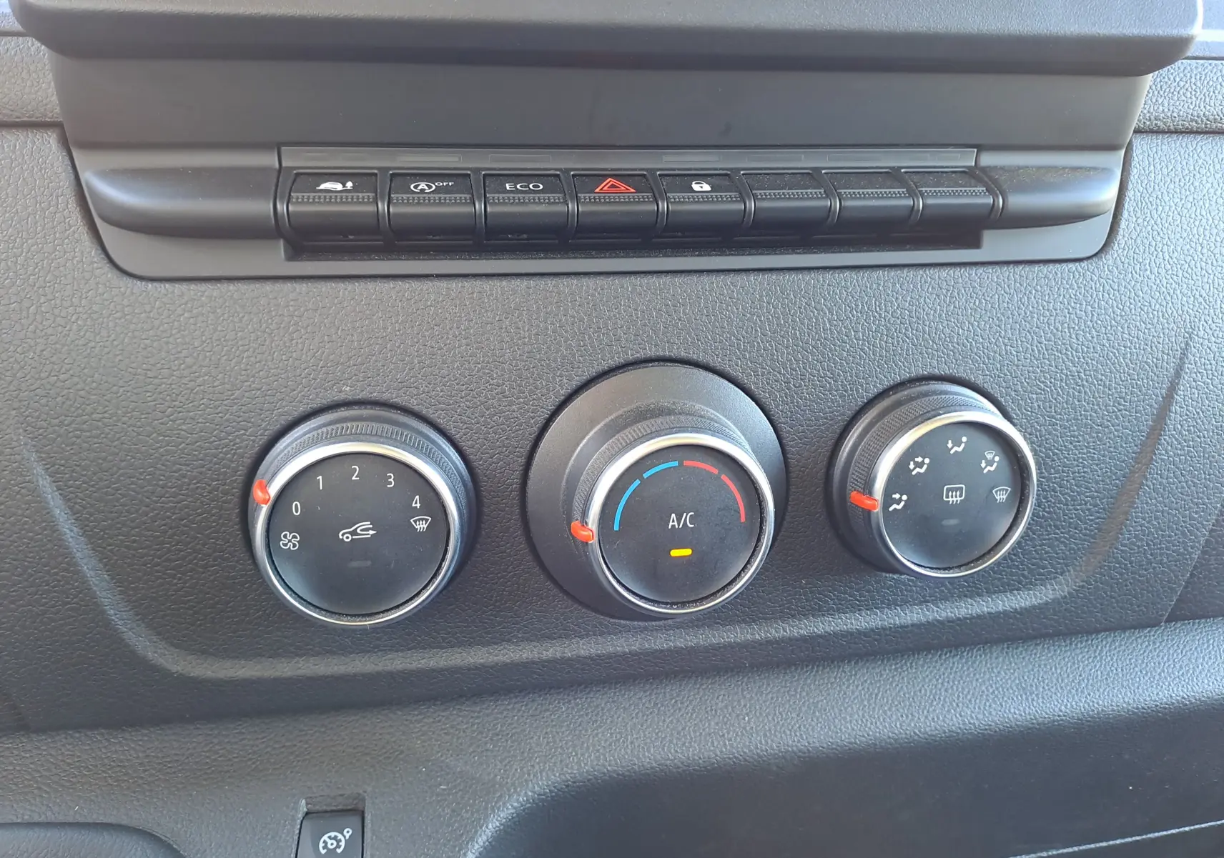 Gros plan sur les commandes de climatisation et boutons de fonction du tableau de bord noir du Nissan Interstar Chassis Cabine blanc 2024.