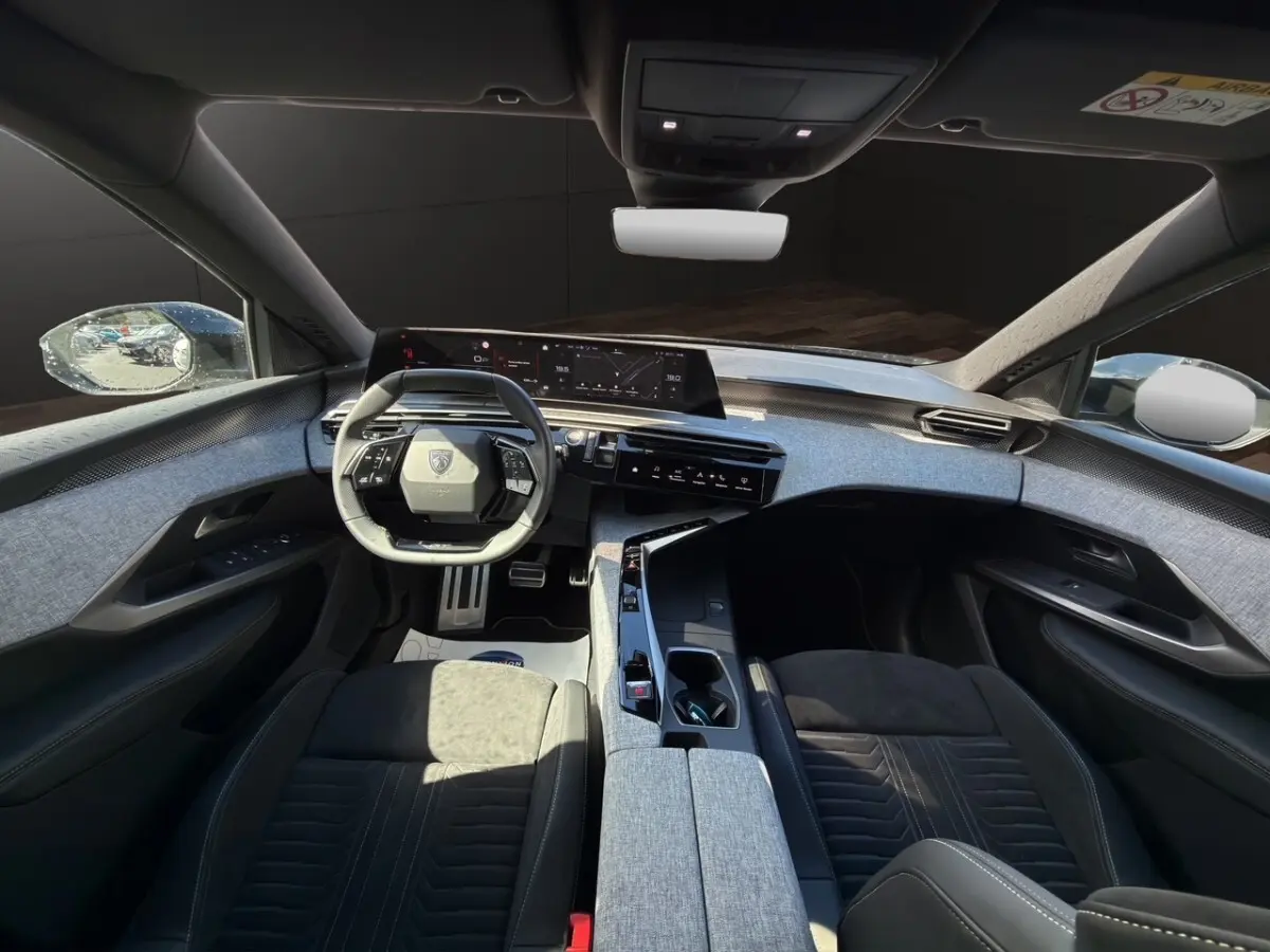 Vue intérieure avant du Peugeot 5008 gris foncé, avec volant compact et tableau de bord numérique large.
