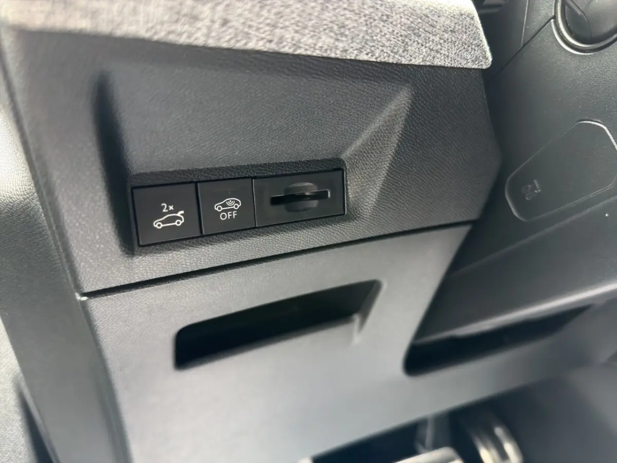 Gros plan sur les commandes de coffre électrique et désactivation de l'assistance, intérieur noir du Peugeot 5008 gris foncé.