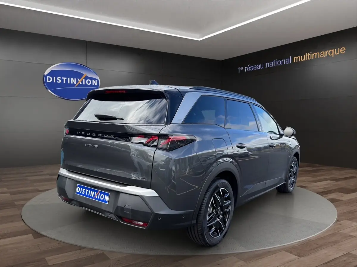 Vue 3/4 arrière droite d’un Peugeot 5008 gris foncé hybride avec jantes noires et feux LED caractéristiques.