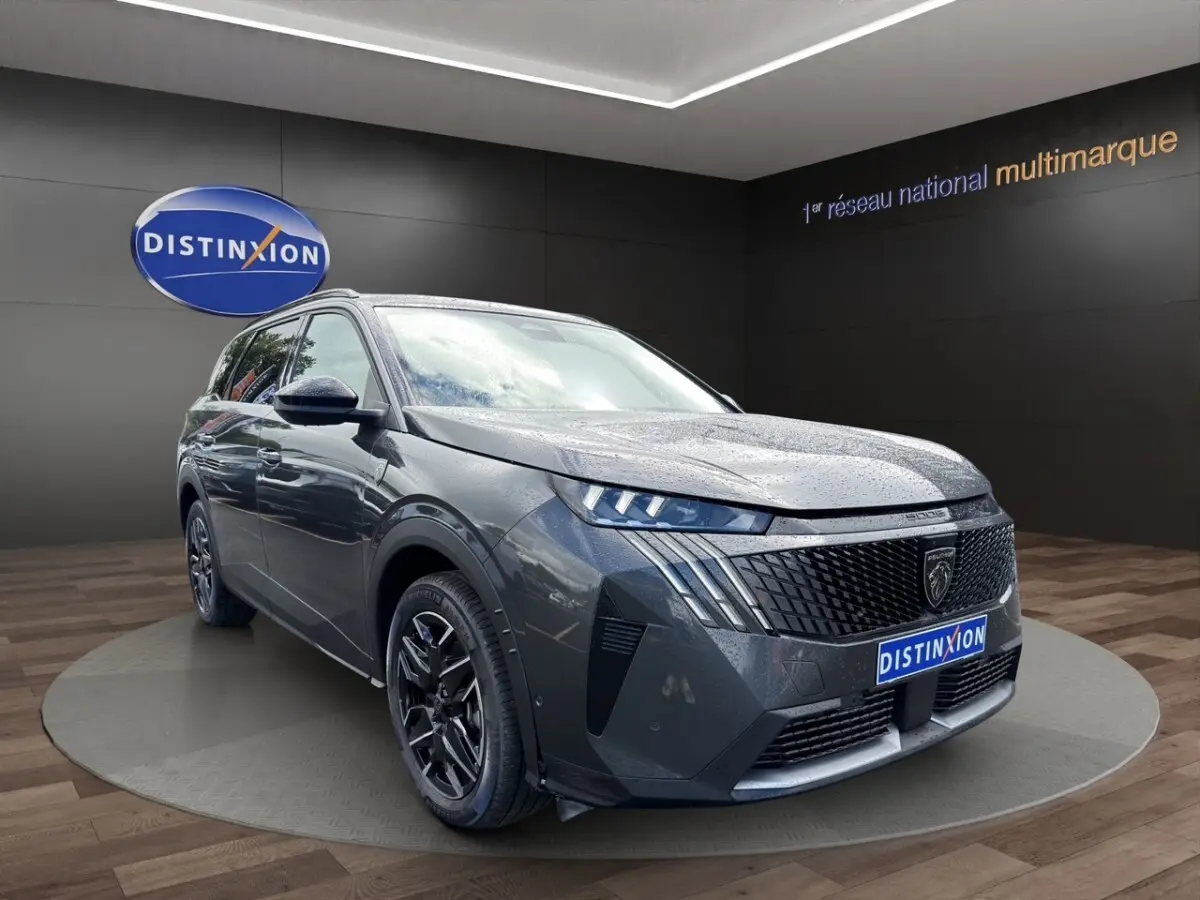 Peugeot 5008 gris foncé vue 3/4 avant, avec calandre noire distinctive et jantes alliage noires.