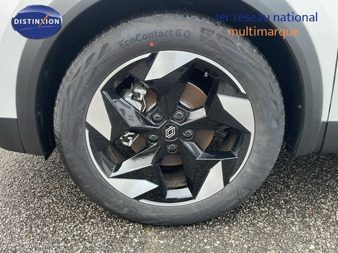 Gros plan sur la roue avant gauche du Renault Captur blanc nacré avec jante noire et argentée au design étoilé.