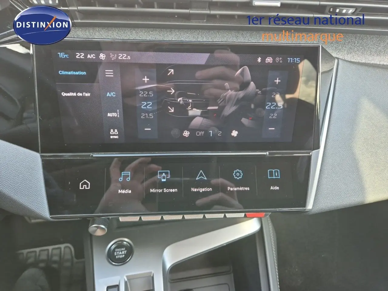 Vue rapprochée de la console centrale tactile de la Peugeot 308 2023 en Vert Olivine, affichant la climatisation et les options multimédia.